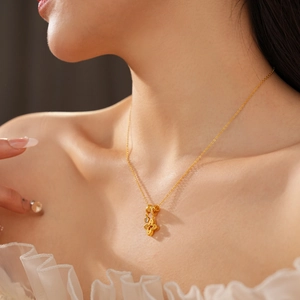 Detail of 18k gold plated four-leaf clover pendant necklace with zircon on a model