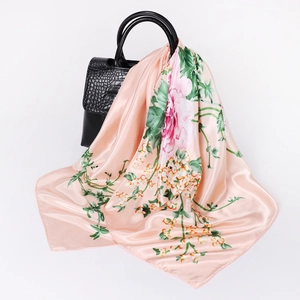 Elegant peach pink silk square scarf with vintage floral patterns draped over a handbag