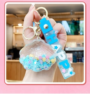 Close-up of shell liquid keychain with blue star sequins and HAPPY letter strap detail