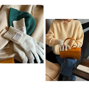 Detail of off-white wool knit gloves featuring minimalist textile label and model styling