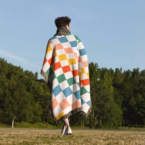 Detailed texture of bohemian colorful checkered knit blanket with fringe tassels in nature