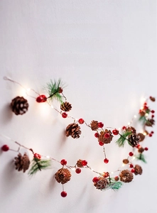 Macro detail of red berries and pine cones on warm white LED Christmas string light