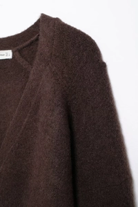 Nahaufnahme eines flauschigen, dunkelbraunen Strickpullovers mit V-Ausschnitt und Label