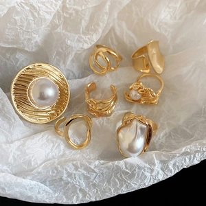 Detailed view of vintage gold plated rings with pearls on wrinkled white paper