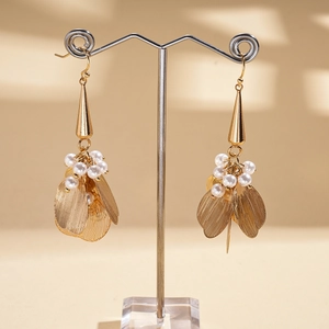 Detail view of gold petal drop earrings with mesh texture and white pearls