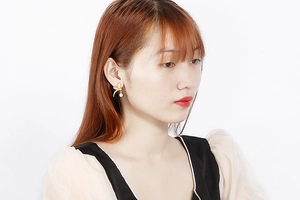 Close-up of gold flower leaf earrings with white pearl drop on a female model