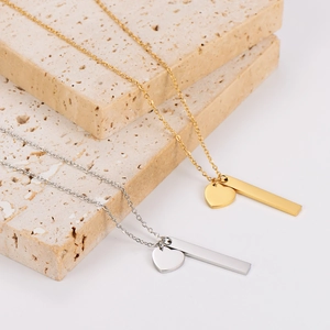 Elegant gold and silver heart bar necklaces in stainless steel on a stone base