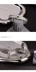 Detail of silver lace woven bracelet featuring a round green gemstone and zircon inlays