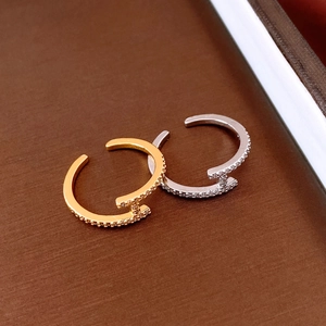 Nahaufnahme goldener und silberner C-Ringe mit Pavé-Zirkonia auf Lederhintergrund