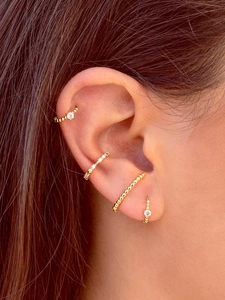 Close-up of gold ear cuff set with micro-pave cubic zirconia on female model's ear