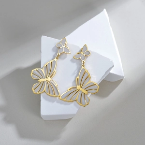 Vintage style butterfly tassel earrings in gold-toned titanium steel on a white stone base