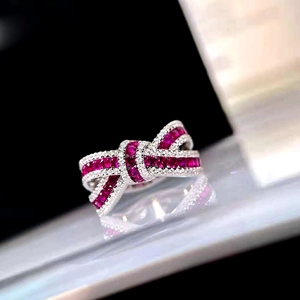 Macro shot of bow ring with ruby zircons and white stone pavé in silver setting
