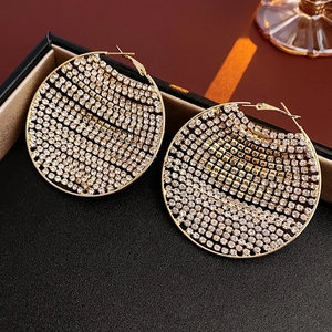 Gros plan de boucles d'oreilles rondes dorées avec zircons dans un écrin à bijoux