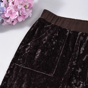 Detail of dark brown velvet trousers featuring an elastic ribbed waistband and side pockets