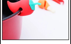 Close-up of a red chili-shaped silicone lid lifter clipped on a pot edge for steam release