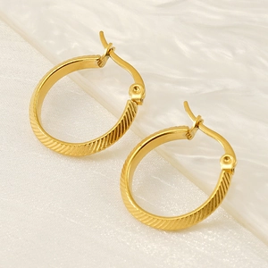 Golden oval hoop earrings with striped texture in 18K stainless steel on white silk