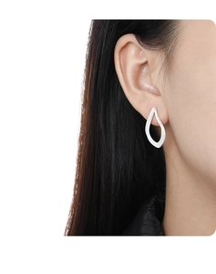 Close-up of matte silver hollow teardrop earrings with a brushed metallic texture
