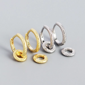 Top view of gold and silver textured hoop earrings with dangling charms on grey background