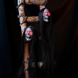 Macro view of hanging Halloween skulls with glowing red eyes and long black hair decor
