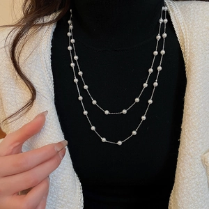 Détail d'un collier double épaisseur en argent avec perles blanches porté par un mannequin