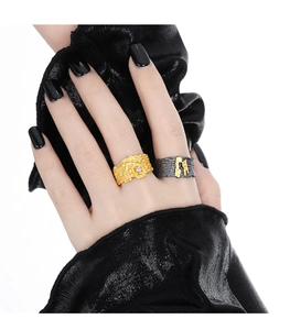 Detailed view of textured gold rhinestone ring and dark charcoal portrait ring on hand