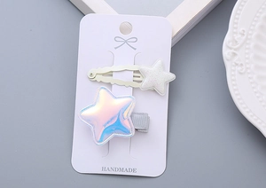 Detail of glitter and holographic star hair clips on white card, handmade for girls