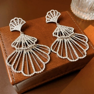 Detail of shimmering multi-layered fan earrings with sparkling rhinestones on leather case