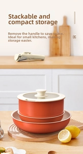 Stackable orange non-stick cookware set with detachable handle and glass lid detail