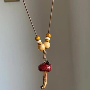 Detail of mushroom pendant necklace with wooden beads and pine cone on a brown cord