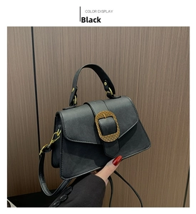 Close-up of black matte shoulder bag featuring a gold diamond buckle on the flap