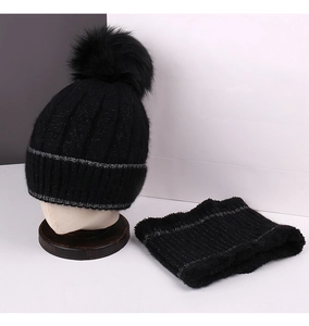 Detail of black knitted beanie with faux fur pompom and matching winter neck warmer set
