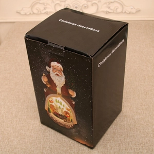 Retail packaging of Christmas music box in black box with white decorative text