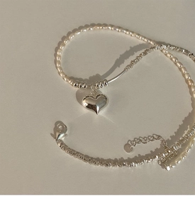 Detail of S925 sterling silver heart pendant with white pearls on a minimalist necklace