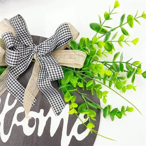 Close-up of wooden welcome sign with buffalo plaid bow and eucalyptus greenery