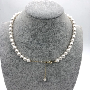 Detailed view of white pearl necklace with gold lobster clasp and adjustable extension chain