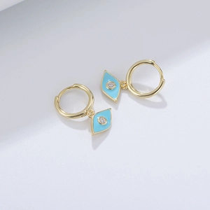 Detail of gold evil eye hoop earrings with blue enamel and white zircon stone