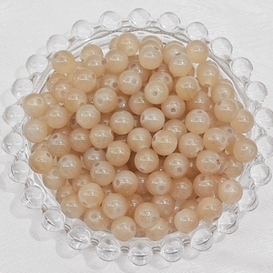 Detail of round champagne glass beads in a clear tray for DIY jewelry making