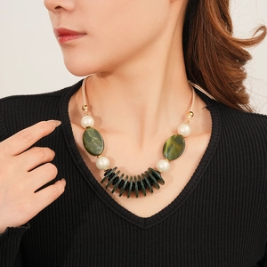 Detail of vintage layered necklace with green oval beads and white spheres on a model