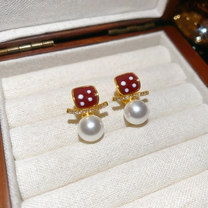 Macro shot of dice-shaped red earrings with crystal accents and white pearls