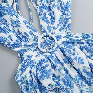Detail of waist design on floral maxi dress featuring pleated fabric and a round button buckle