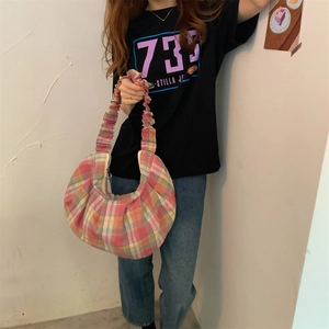 Detail of pink plaid pleated shoulder bag with crescent shape and ruched strap design