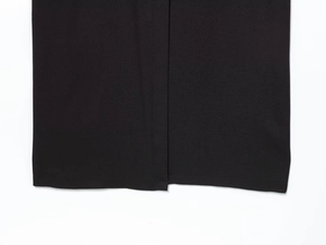 Détail de la fente de l'ourlet et coutures précises sur la robe midi noire à manches