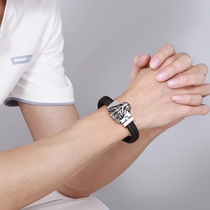 Détail du bracelet tressé en cuir noir pour homme avec fermoir tête de lion en acier argent
