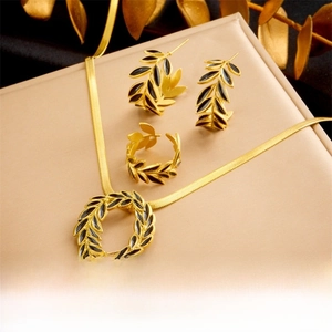 Close-up of gold leaf jewelry set featuring black enamel necklace, earrings and ring