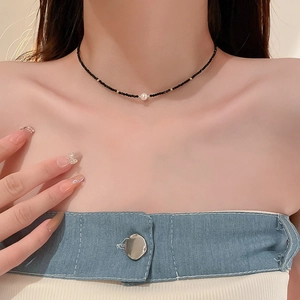 Détail d'un collier minimaliste avec perles noires et pendentif en perle blanche