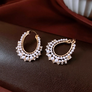 Detail of vintage gold pearl earrings with sparkling rhinestones on leather background