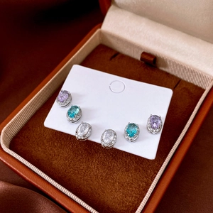 Close-up of oval zircon earrings in purple, blue, and clear sets inside a velvet box