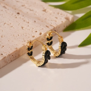 Detail of vintage gold U-shaped earrings with black wheat leaf zircon inlays