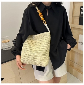 Detail of hand-woven straw shoulder bag with stylish wooden bead strap for women