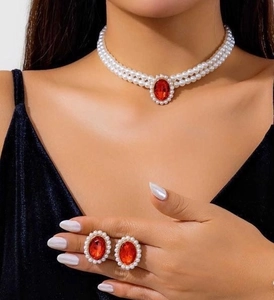 Detail of elegant double-row pearl necklace and ruby earrings set on black velvet dress